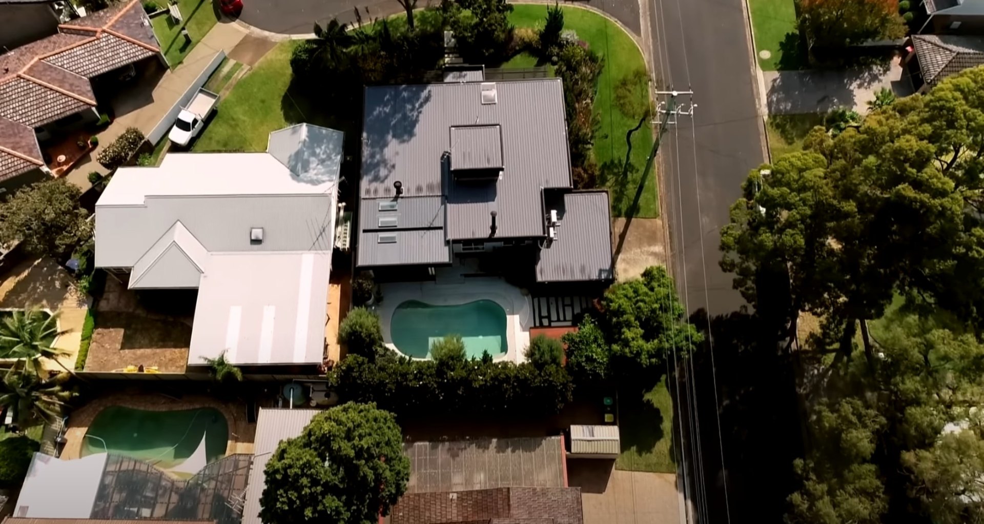 Complete Residential Landscape Design with Pool and Mature Plantings Aerial view of residential property with swimming pool, well-maintained lawn, and mature landscape design in suburban setting